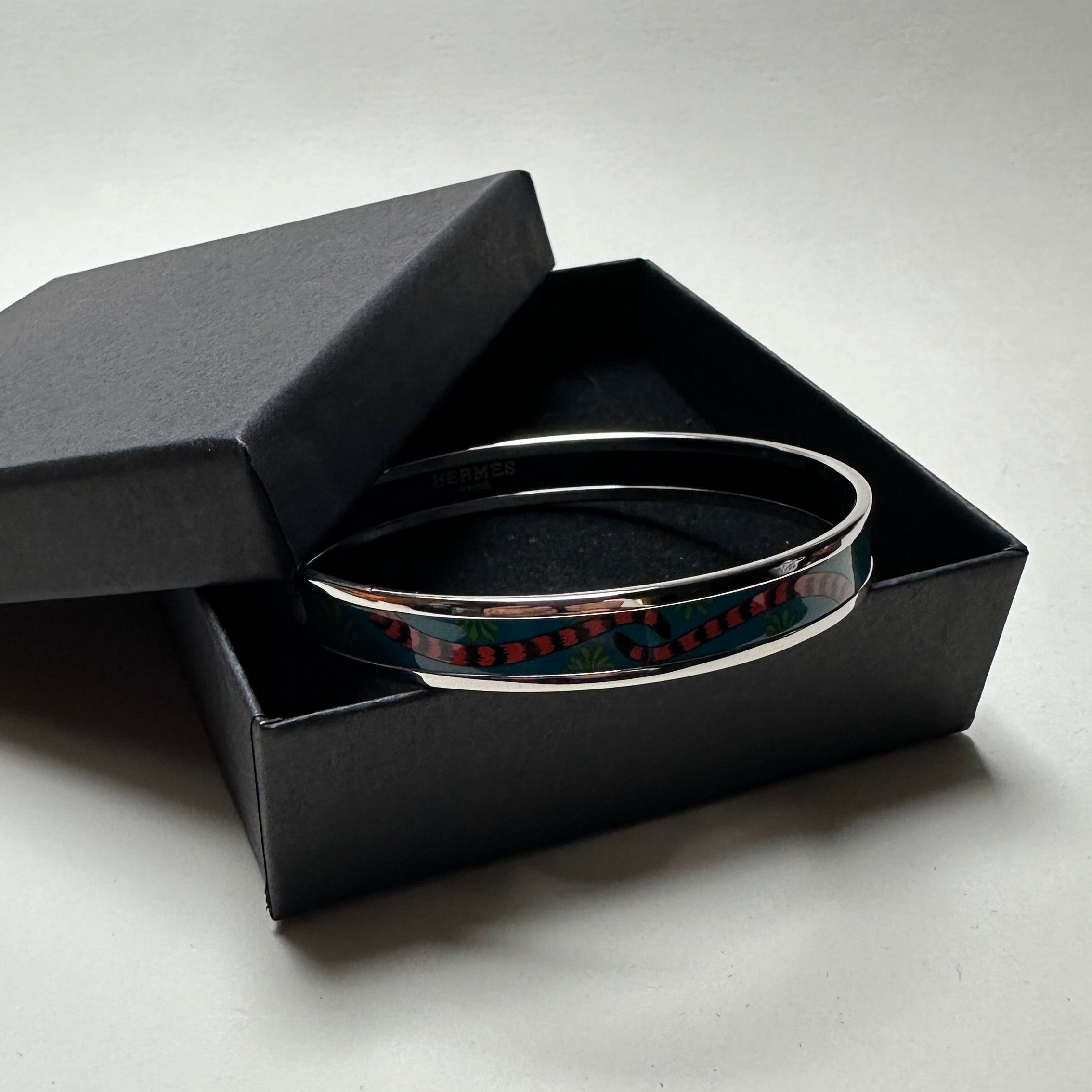 Bracelet jonc Hermès vintage en émail bleu motif Tigre Royal et finition palladium, présenté dans un écrin noir.