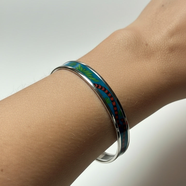 Bracelet jonc fin Hermès porté au poignet, montrant l'élégance de l'émail bleu et de la bordure argentée palladium.