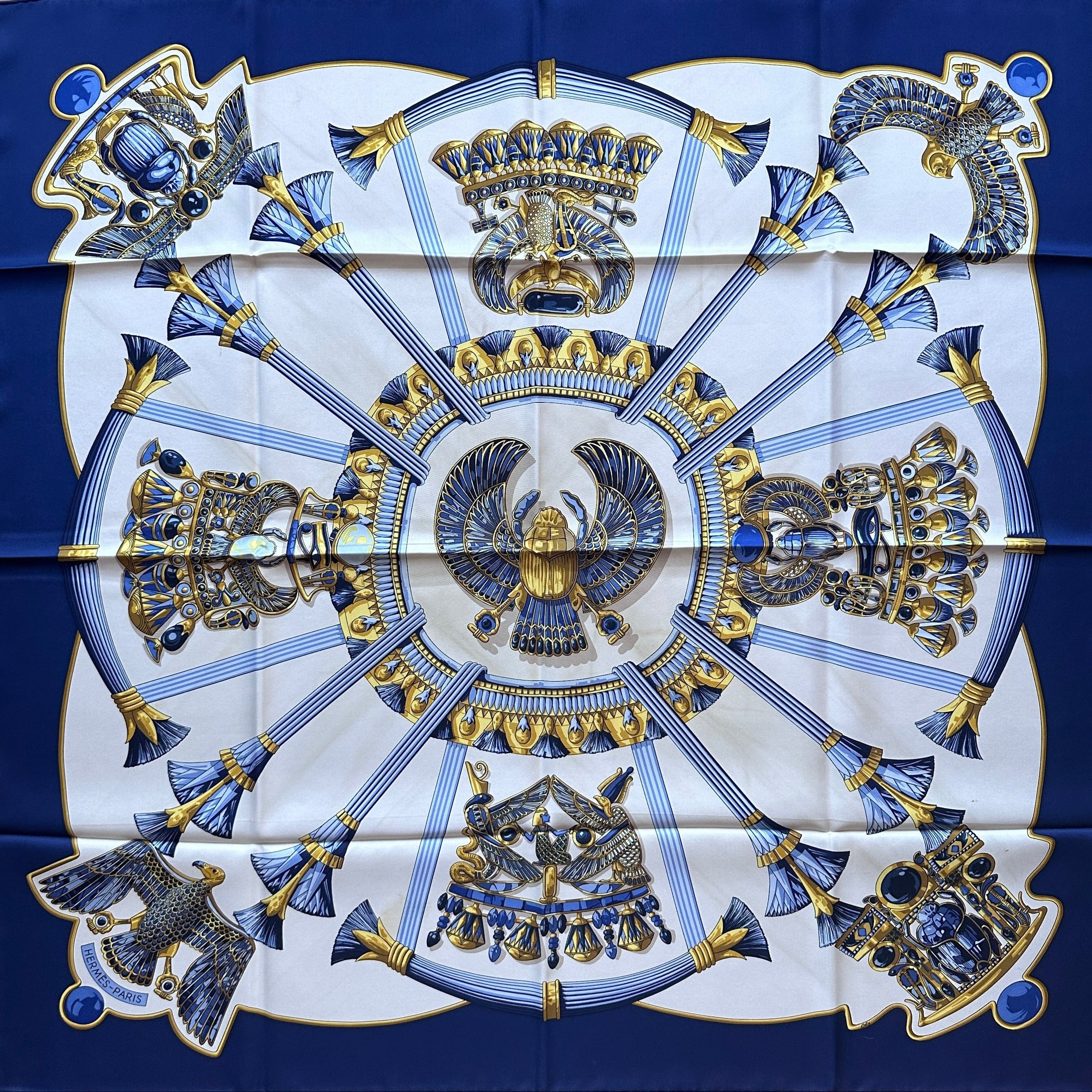 Carré Hermès Égypte en soie, design symétrique bleu marine, blanc et or avec motifs antiques.