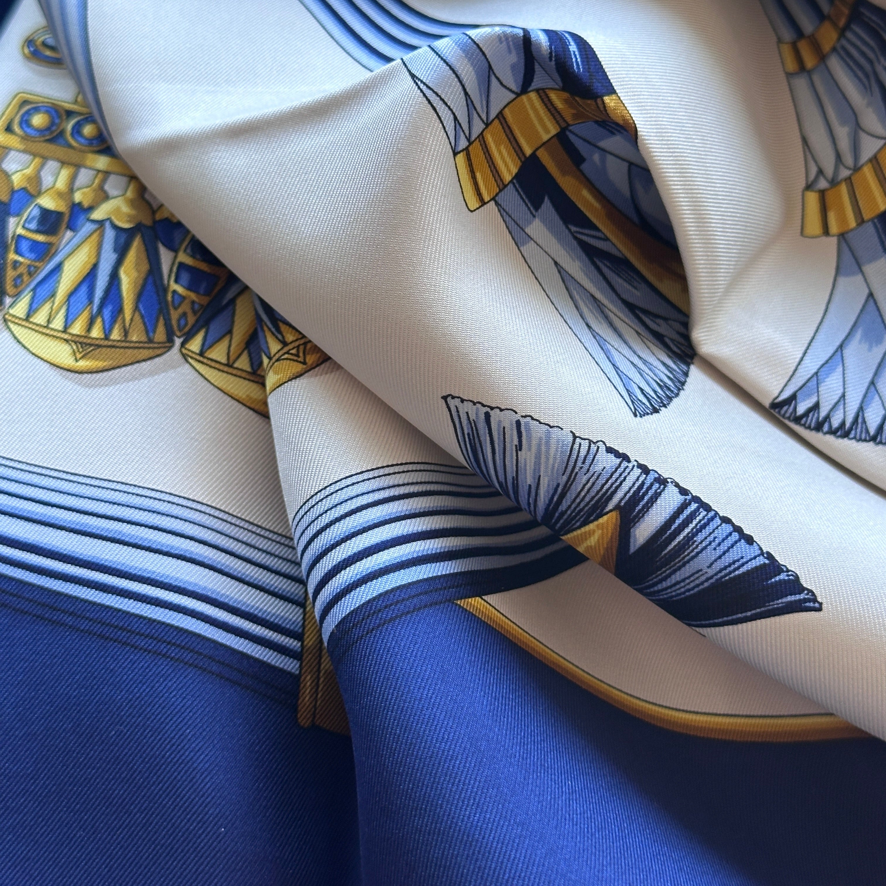Foulard Égypte plié montrant la fluidité de la soie et les contrastes bleu/blanc.