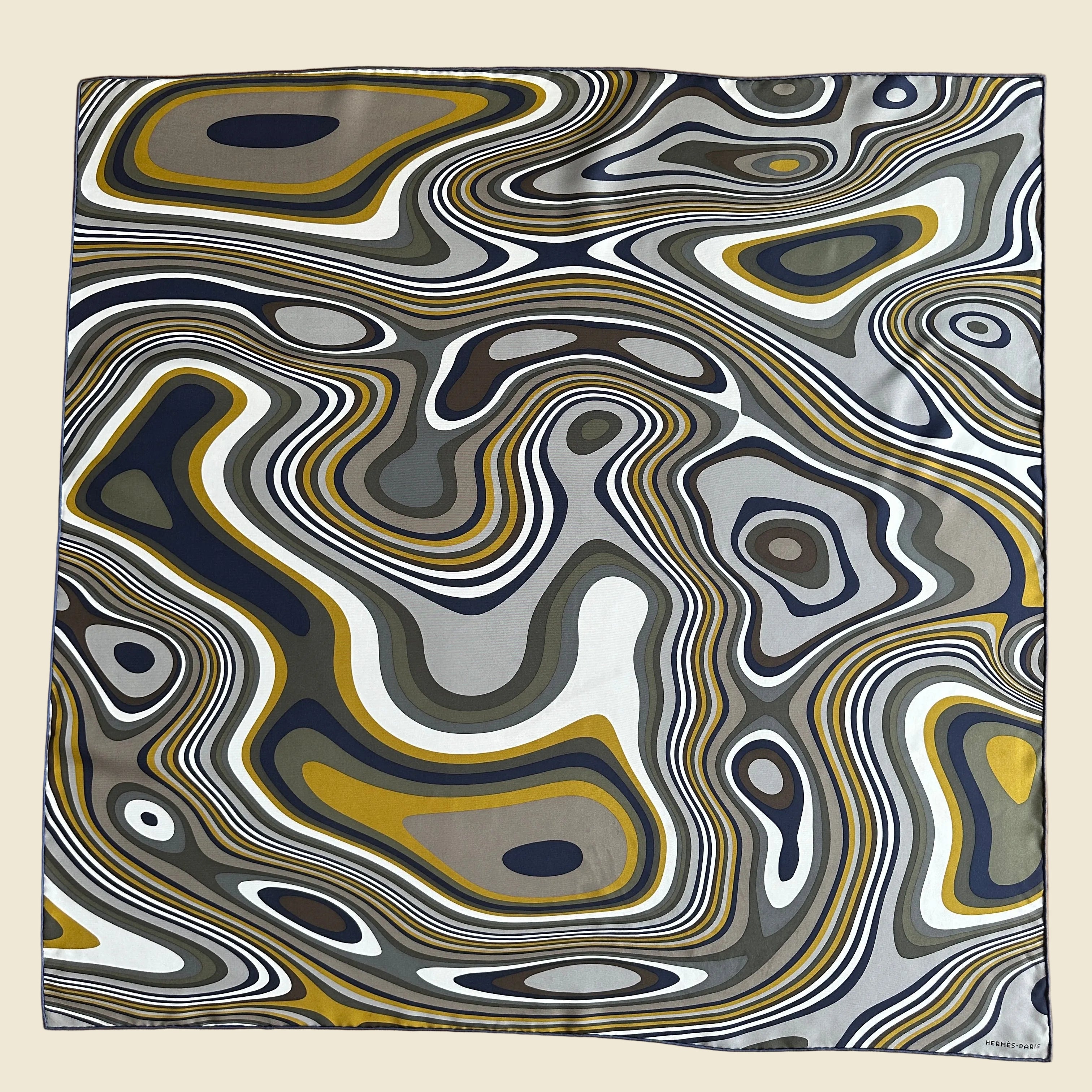 vue d'ensemble du Carré Hermès Homme 100cm "Rêve Hypnotique" signé Miguel Chevalier. Motif graphique d'ondes psychédéliques en gris, ocre moutarde, blanc et bleu marine.