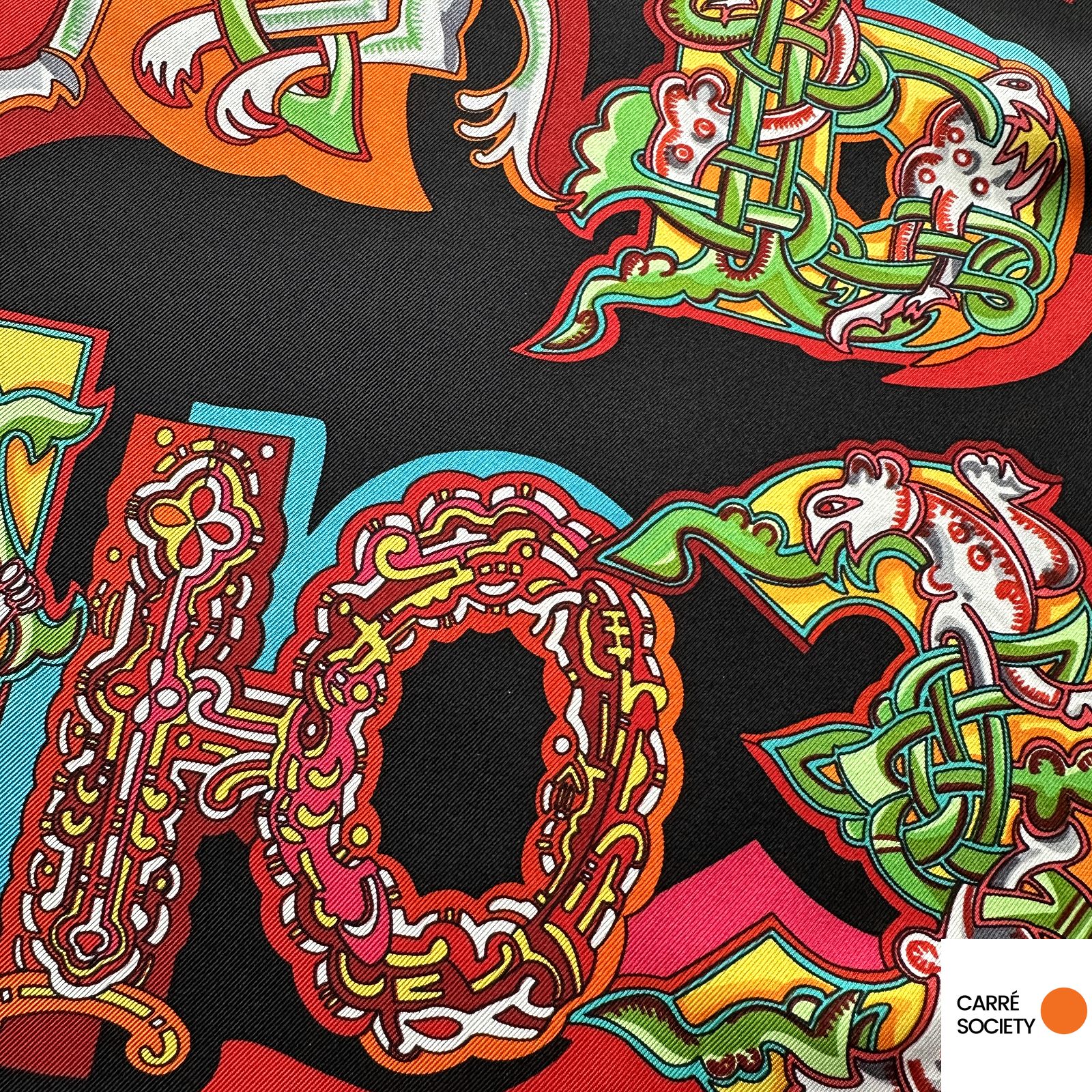 Lettre décorative agrandie : détail d’une lettre cyrillique stylisée en rouge, vert et or.