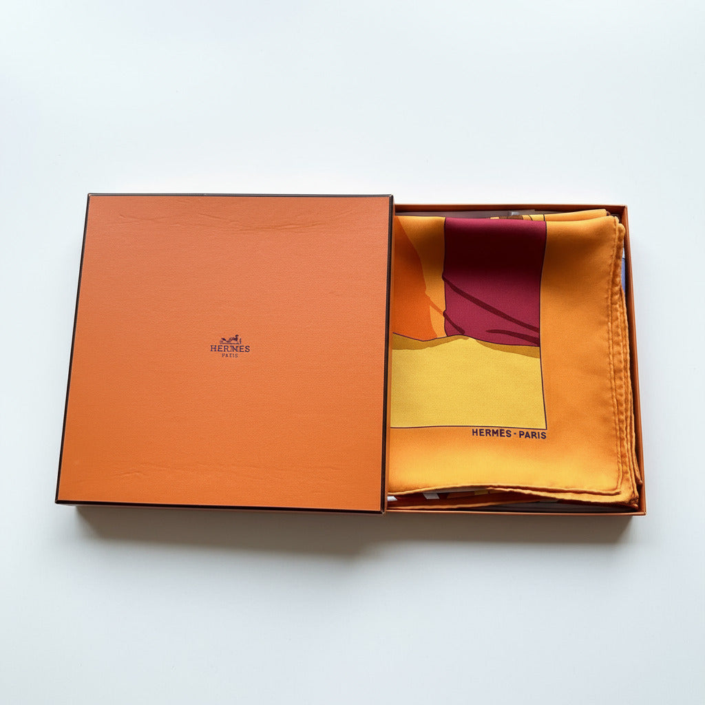 Foulard Hermès Charmes des Plages Normandes II soigneusement plié dans sa boîte orange Hermès