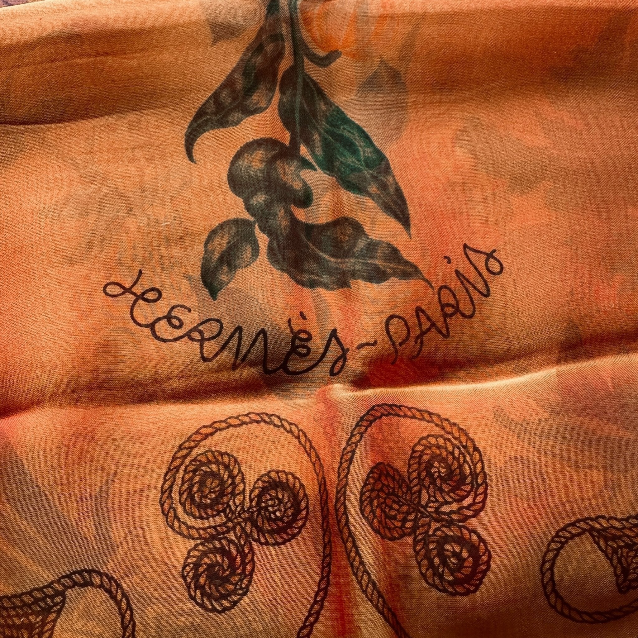 Gros plan de la signature "HERMÈS-PARIS" sur la mousseline de soie du châle.