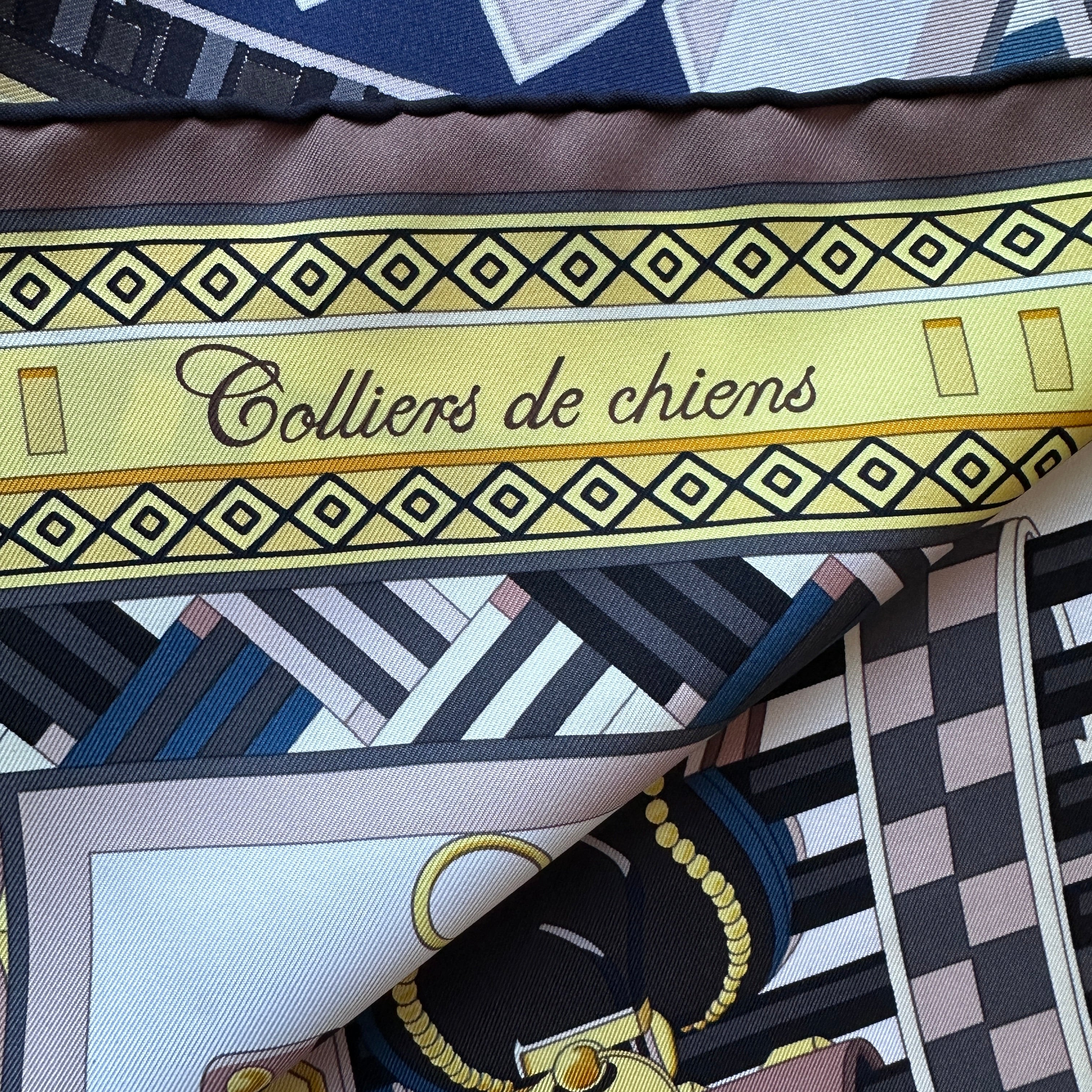 Zoom sur l'inscription cursive "Colliers de chiens" sur fond géométrique.