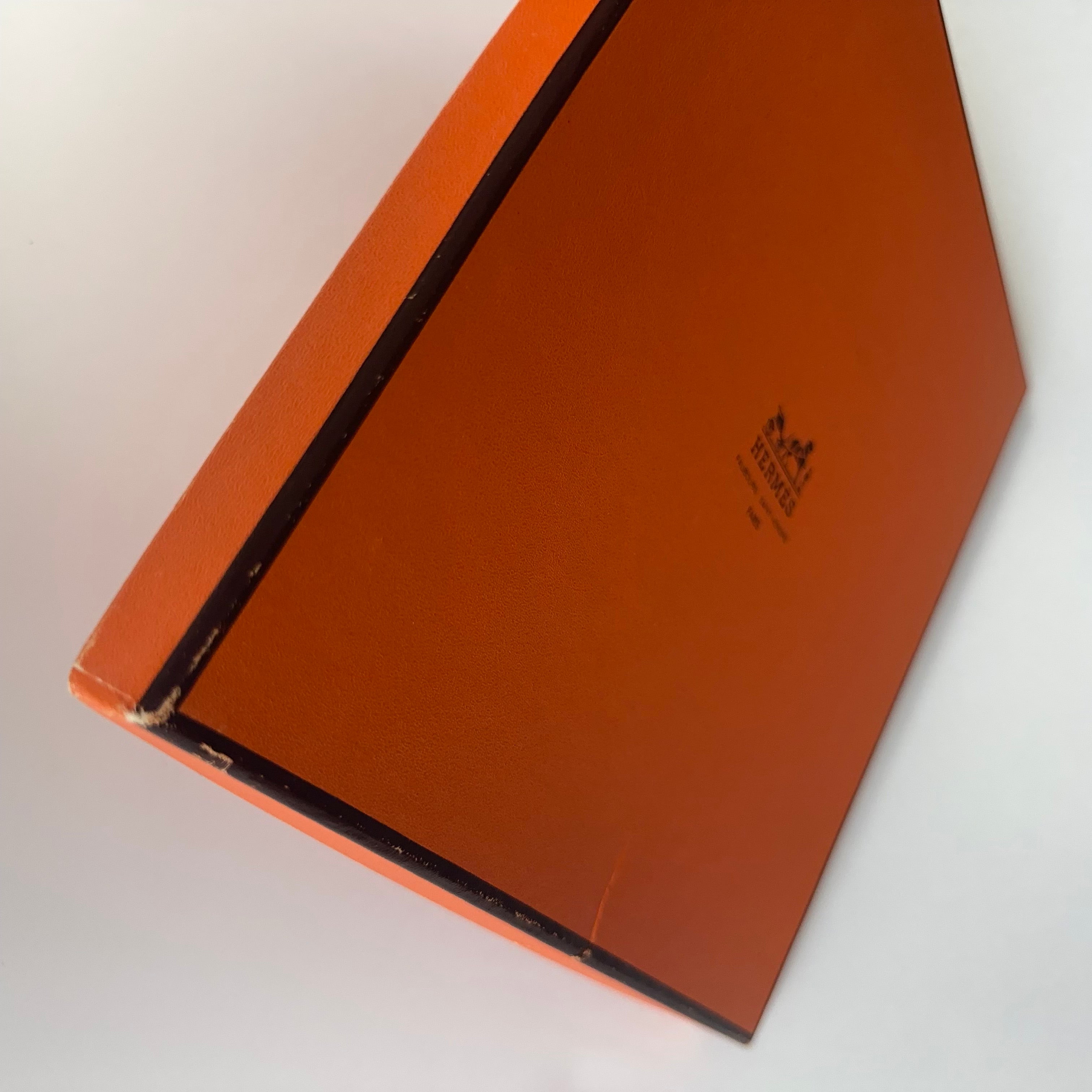Vue de détail montrant les traces d'usure et petits défauts sur le couvercle de la boîte orange Hermès fournie avec le foulard (mentionnés dans la description).